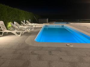 a swimming pool with white chairs and a group at Villa Meraki experiencia in San Miguel de Corneja