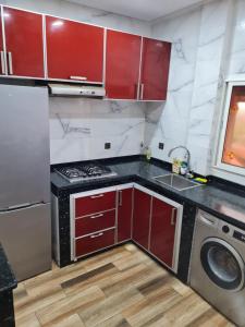 a kitchen with red cabinets and a washing machine at Adnani in Temara