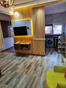 a living room with a flat screen tv and wooden floors at Adnani in Temara +2 photos