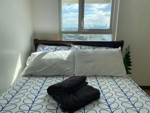 a bed with two pillows on it with a window at Gradient Sky in Manila