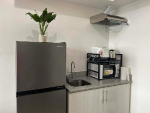 a kitchen with a sink and a refrigerator with a plant on top at Gradient Sky in Manila