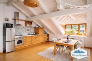 a kitchen with a table and a refrigerator at ChiemseeRefugium - Ferienwohnung Park in Bernau am Chiemsee +8 photos