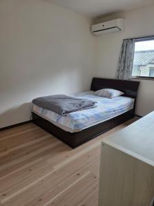 a bedroom with a bed in a room with a window at Daizaifu Guest House 1 in Dazaifu