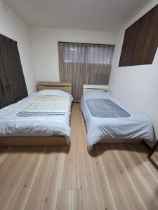 a bedroom with two beds and a wooden floor at Daizaifu Guest House 1 in Dazaifu