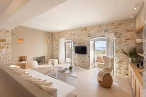 a living room with white furniture and a stone wall at Villa Caelia in Santa Maria