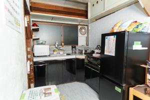 a small kitchen with a black refrigerator and appliances at FLORAhouse in Oita