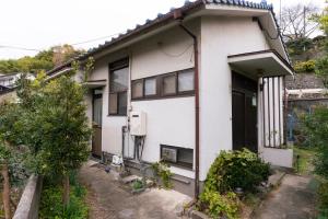 a white house with a tree in front of it at FLORAhouse in Oita