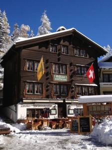 a large wooden building with flags on it in the snow at Gasthaus zum Sternen in Andermatt