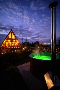 a hot tub in front of a house at night at The Retreat Marisel in Mărişel