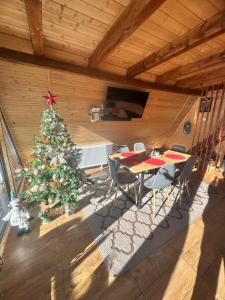 a christmas tree in a room with a table and chairs at The Retreat Marisel in Mărişel