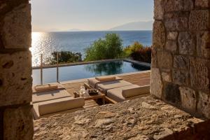 a view of a swimming pool from a stone wall at KOIA All - Suite Well Being Resort - Adults Only in Ágios Fokás