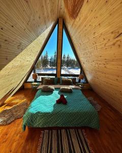 a bed in a room with a large window at The Retreat Marisel in Mărişel +52 photos