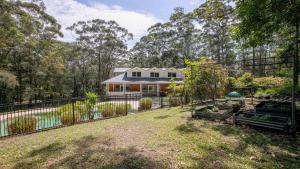 a house with a fence in front of a yard at Nirvana Estate Macmasters Beach in Macmasters Beach