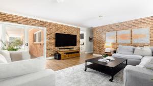 a living room with a brick wall at Nirvana Estate Macmasters Beach in Macmasters Beach +16 photos