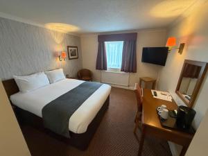 a hotel room with a large bed and a desk at Raven Hotel by Greene King Inns in Hook