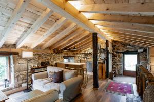 a living room with wooden ceilings and a stone wall at Cabañas con Encanto in San Roque de Ríomiera