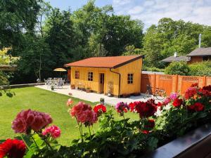a small yellow house in a yard with flowers at Haus an der Mur in Mureck