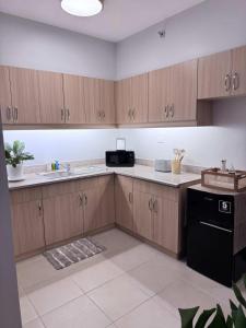 a kitchen with wooden cabinets and a black appliance at Alea Residences 1 Bedroom Condo with Pool View Balcony in Manila