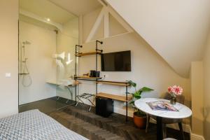 a room with a bed and a table and a tv at Hotel Bloemendaal by BHC in Bloemendaal