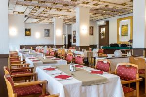 a dining room with white tables and chairs at Hotel Árpád in Tatabánya