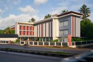 a building on the side of a road with a person on a motorcycle at CASTELO Inn in Nedumbassery
