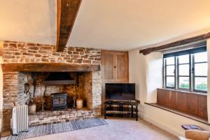 a living room with a stone fireplace and a television at Finest Retreats - Syncocks Farm Cottage in Petrockstow