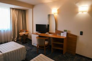 ein Hotelzimmer mit Schreibtisch, Fernseher und Bett in der Unterkunft Triada Hotel in Sofia