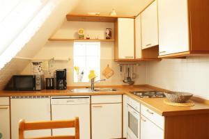 a kitchen with white cabinets and a sink at Ferienhaus - Kann in Vollerwiek