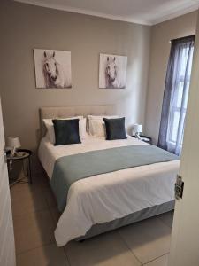 a bedroom with a large bed with two pictures of horses on the wall at Oak and Olive Retreat Midrand in Midrand +18 photos