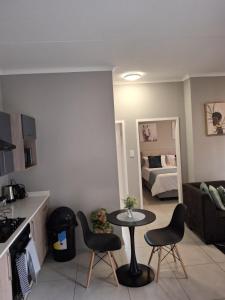 a kitchen and a living room with a table and chairs at Oak and Olive Retreat Midrand in Midrand