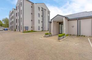 a row of white buildings in a parking lot at Oak and Olive Retreat Midrand in Midrand