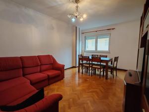 a living room with a red couch and a table at Apartamentos Quien Anda Ahí Ribadeo in Ribadeo