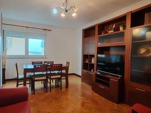 a living room with a dining room table and a television at Apartamentos Quien Anda Ahí Ribadeo in Ribadeo