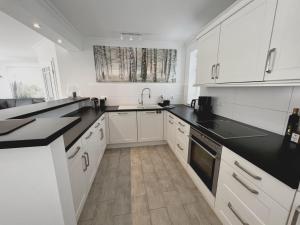 a kitchen with white cabinets and black counter tops at Dorf 36 in Ording +5 photos