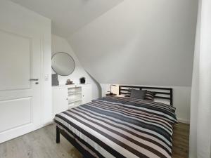 a white bedroom with a striped bed and a dresser at Dorf 36 in Ording