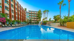 a swimming pool at a hotel with chairs and palm trees at CLUB MONTE CARLO HoTEL in Alanya