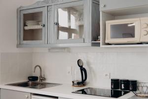 a white kitchen with a sink and a microwave at La Marmittiere in Civray-de-Touraine