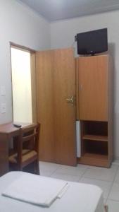 a room with a desk and a cabinet with a television at Hotel Pousada Viana in São Paulo