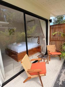 a bedroom with a bed and a chair on a balcony at Srithanu Escape 1 in Srithanu