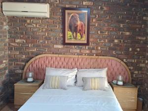 a bed in a room with a brick wall at Carey 43 in Bothaville +13 photos