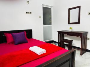 a bedroom with a red bed and a desk at Yala Dream Wild Resort in Tissamaharama