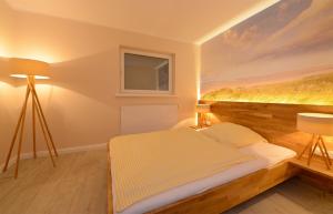 a bedroom with a bed with a painting on the wall at Wenningstedt Beach Apartment in Wenningstedt