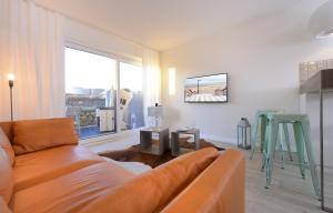 a living room with a couch and a large window at Wenningstedt Beach Apartment in Wenningstedt