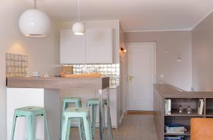 a kitchen with blue stools and a counter in a room at Wenningstedt Beach Apartment in Wenningstedt