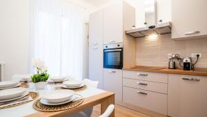 a kitchen with white cabinets and a table with chairs at Ramazzini District – Elegant Flat x8 in Milan