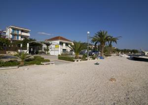 a sandy beach with palm trees and a building at Villa Opatija in Marina