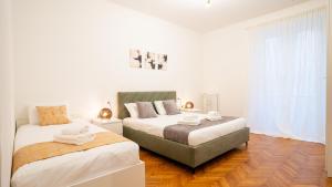 two beds in a bedroom with white walls and wood floors at Ramazzini District – Elegant Flat x8 in Milan