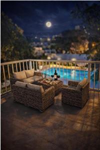 three wicker chairs and a table on a balcony at night at Resort Villa Las Palmeras in Roquetas de Mar