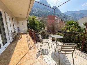 a balcony with a table and chairs and mountains at Golden Bay Apartment in Kotor