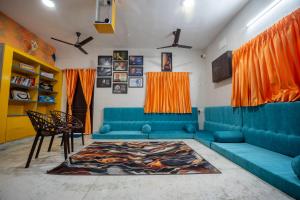 a living room with blue couches and orange curtains at Rayzen Stays & Backpackers Hostel in Chennai